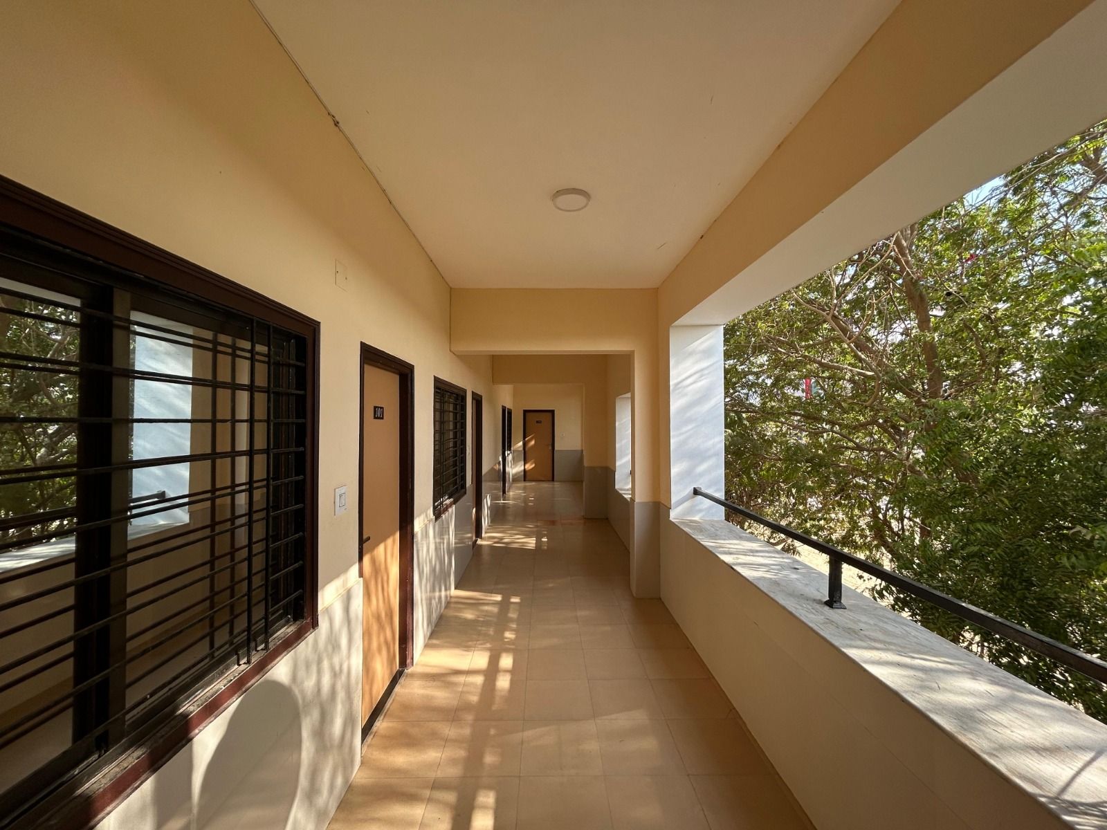 Open first-floor corridor outside the rooms, beside the trees