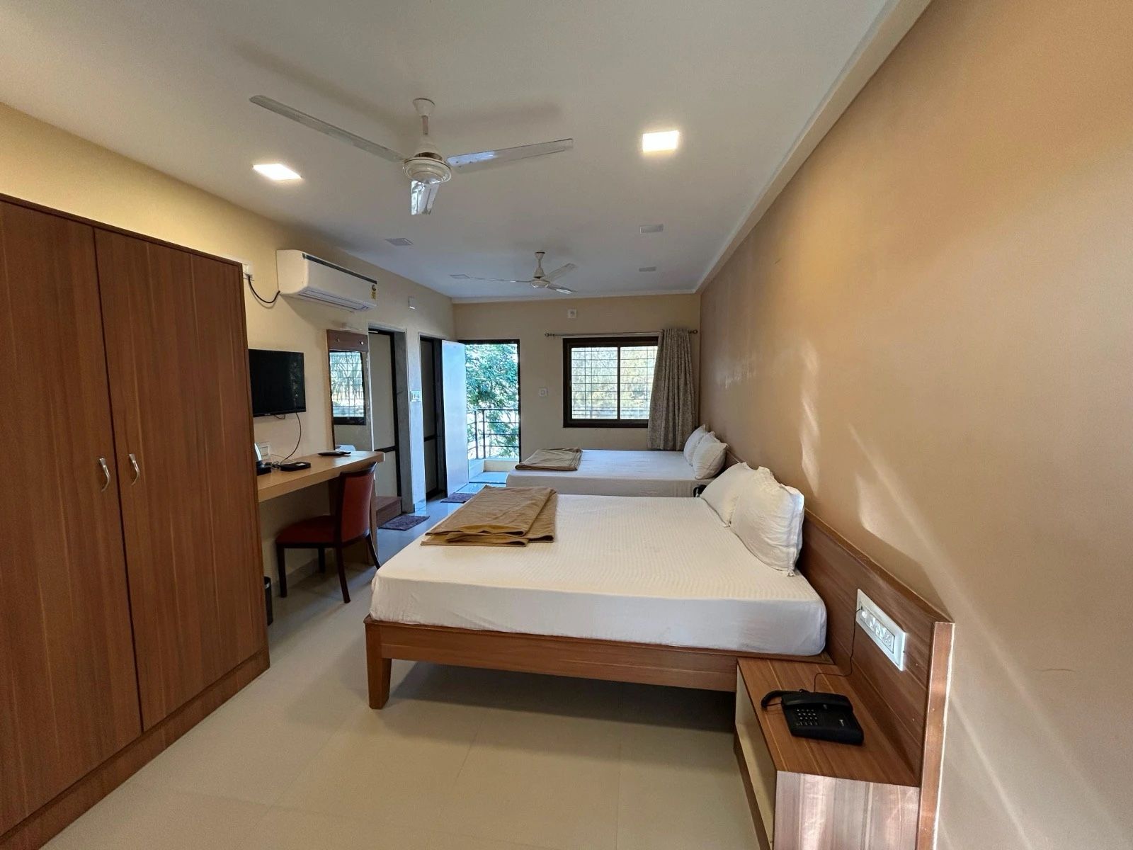 Premium 4-Bed AC room with two double beds, a wardrobe, a desk, a TV and a door to the balcony